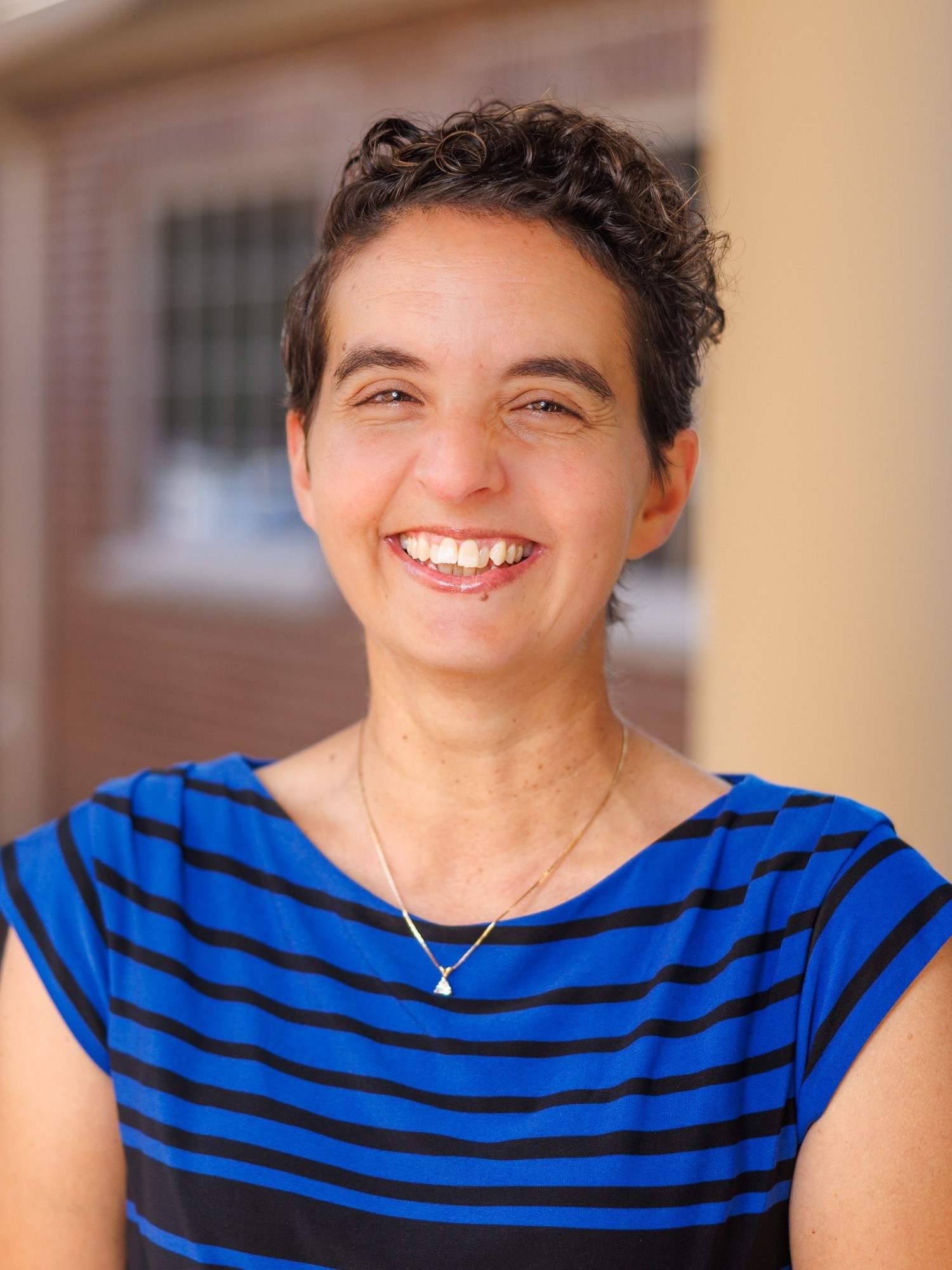Susan Miller headshot wearing blue shirt with black horizontal stripes
